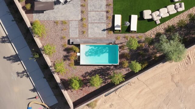 Stable overhead drone view shows a landscaped residential pool courtyard framed by neighboring homes and trees.