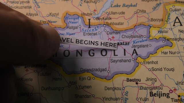 Paper Snippet with Text Travel Begins Here Placed on Mongolia Map