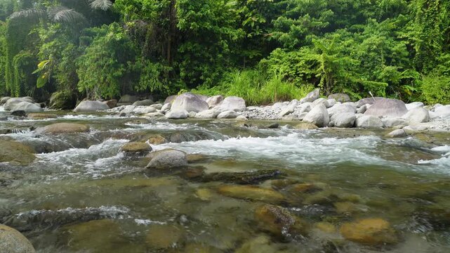 Wide Tropical River Flowing Across Rocky Riverbed 4K