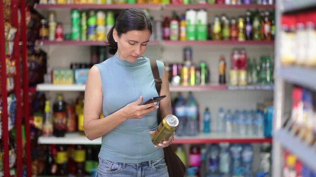 woman buyer scans barcode code on beer can in grocery store . High quality 4k footage