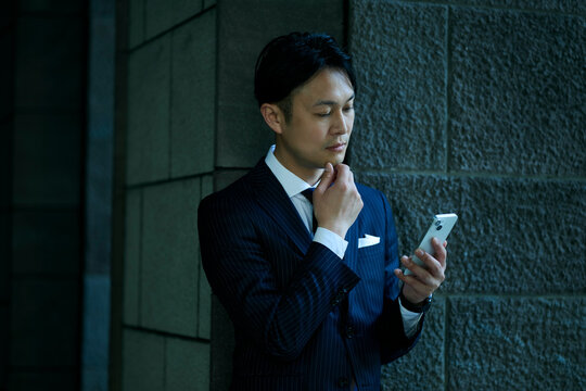 スマートフォンを見て考え込む男性ビジネスマン