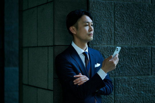 スマートフォンを手に考える男性ビジネスマン