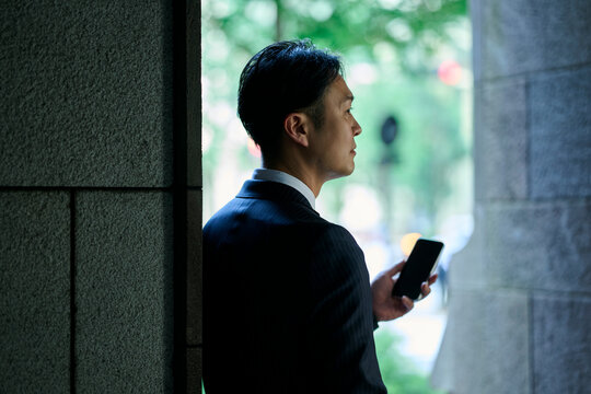 スマートフォンを手に物思いにふける男性ビジネスマンの横顔