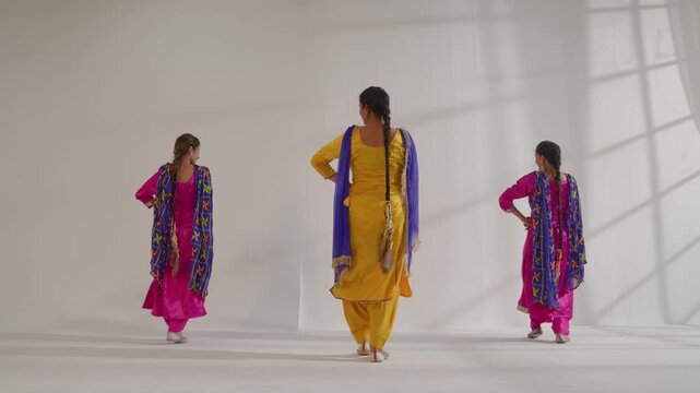 Three women performing a traditional Bhangra dance in an Indian studio