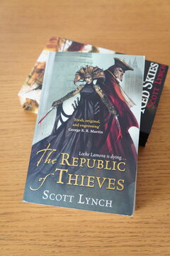 The Republic of Thieves book cover by Scott Lynch displayed on a wooden table surface for readers