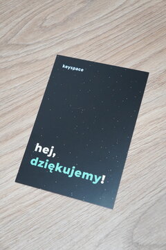 A black thank you card with starry night design and Keyspace branding on a light wooden surface