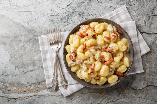 rich and creamy gnocchi carbonara made with homemade pillowy gnocchi and tossed in an easy carbonara sauce with pancetta closeup on the plate on the table. Horizontal top view from above