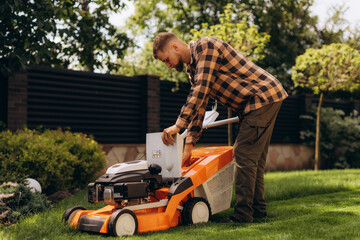Fototapeta premium Man preparing lawn mower for yard work