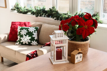 Christmas home decor and holiday countdown, poinsettia plant with candle lantern and wooden calendar on table in cozy living room interior © Pixel-Shot