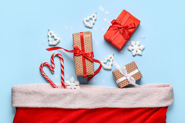 Fototapeta premium Santa bag with gift boxes, candy canes and Christmas trees on blue background