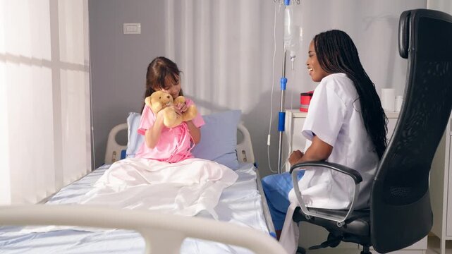 Caucasian girl sit on hospital bed holding toy while talking with doctor. 