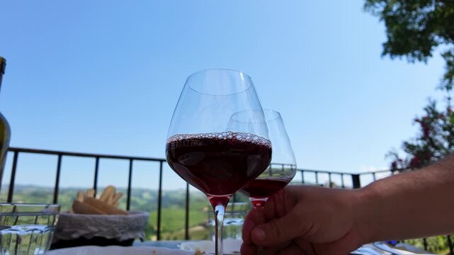 Person Picking Up Glass of Red Wine on Sunny Vineyard Terrace