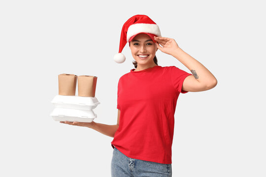 Holiday food delivery service, smiling courier wearing Santa hat holding takeout containers for Christmas season orders on a plain white background