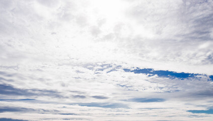 Altocumulus clouds drift over a blue sky, bright cloudscape fading into overcast weather with diffused sunlight. Fluffy white and gray formation spreads across a hazy. Dreamy panorama, copy © valiantsin