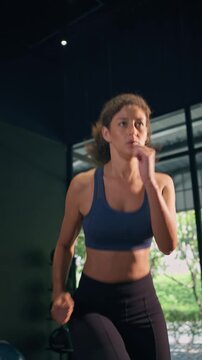 Young Latino athletic woman doing cardio workout in modern fitness gym.