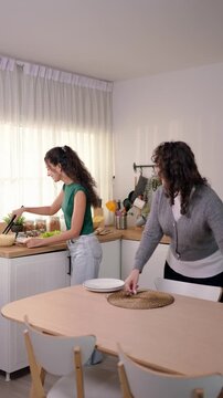 Senior Latino mother and young adult daughter cooking in kitchen at home. 
