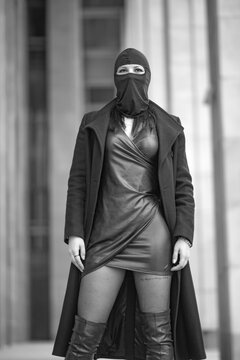 Black and white full length portrait of powerful rebellious woman in balaclava mask and boots with copy space