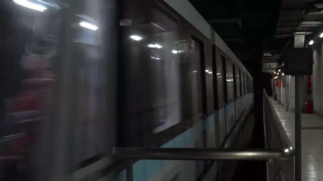 Subway train moving past station platform with motion blur and visible passengers through windows