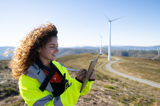White woman engineer using tablet at wind farm in Galicia Spain