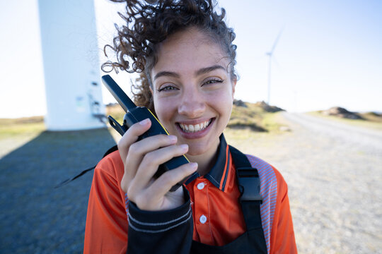 White woman holding walkie talkie at wind farm in Galicia, Spain