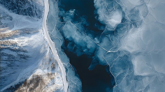 Aerial View of Cracked Frozen Lake with Ice Sheets and Snow-Covered Mountain Shore