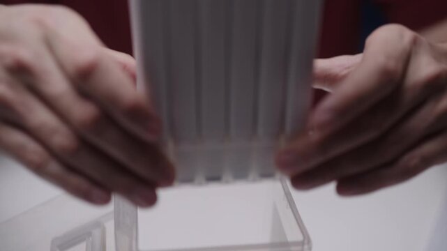Close-up graphic artist hands neatly arranging full collection of double sided felt tip pens into plastic organizer box on clean white desk, ready for illustration, closeup, cropped shot, slow motion.