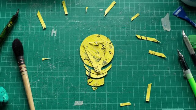 Stop Motion Animation of Light Bulb Idea Symbol Created from Shredded Yellow Paper on Green Cutting Mat