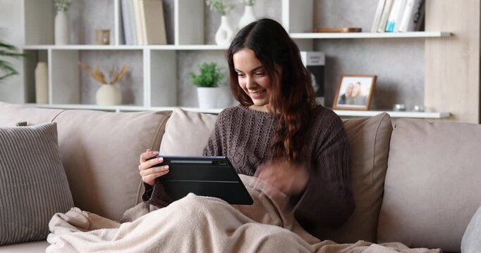 Excited young woman checking tablet at home