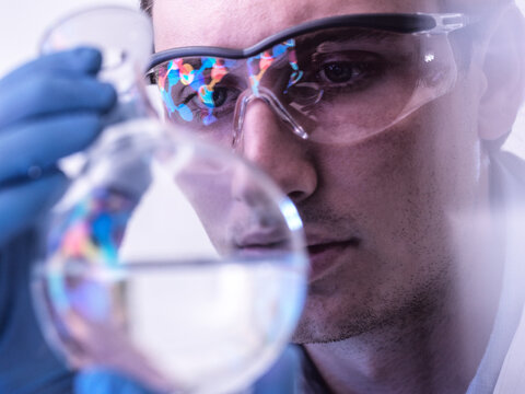 Male scientist examines chemical compound in laboratory flask