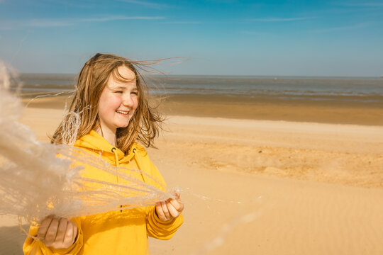 Smiling teenage girl holds plastic garbage during a beach cleanup