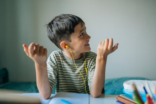 A smiling boy counts on his fingers while doing homework indoors