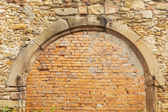 Historic sandstone wall with a bricked up arch gate outdoors