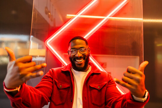 Smiling man in red jacket with neon cyberpunk backdrop nightlife