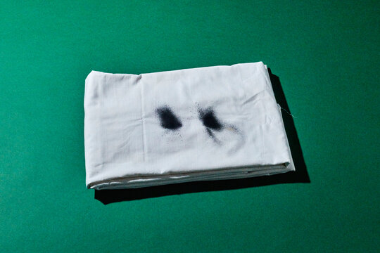 A folded ghost costume lies on a green background