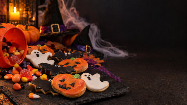 Halloween cookies with candy and cobwebs on a slate board