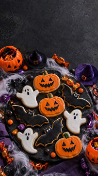 Halloween iced cookies with bats, ghosts and pumpkins on slate