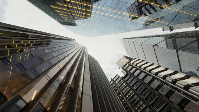Vertical urban canyon formed by glass towers and reflections in London England where architecture rises around the canyon and emphasizes the towers