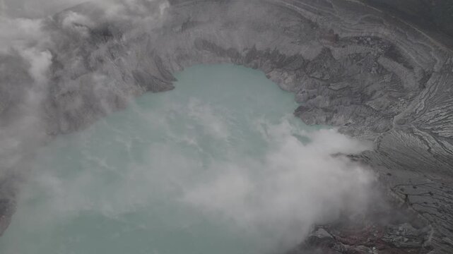 Aerial View of Turquoise Volcanic Ijen Crater Lake Surrounded by Steam and Sulfur Gas Clouds in a Barren Rugged Landscape at Banyuwangi, East Java, Indonesia