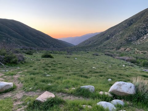 Mountain valley landscape at sunset with green hills and clear sky