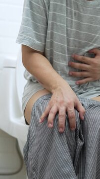 portrait of a man suffers from diarrhea his stomach painful. ache and problem. in front of toilet bowl. constipation in bathroom. Hygiene, health care concept.