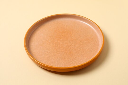 Empty orange plate on beige background