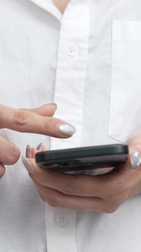 woman holds smart phone in her hands and scrolls through the news feed. Close up of hand uses mobile. point finger on screen, texting text message.