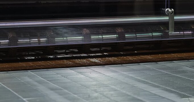 Automated wafer sheet production line operates at food factory. Freshly baked wafer material moves through industrial processing equipment before cone forming