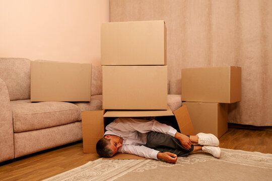 Exhausted man sleeps inside a cardboard box during a stressful move