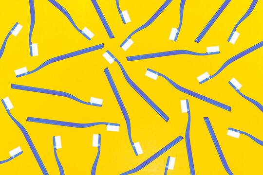 Pattern of scattered blue toothbrushes on a vibrant yellow background