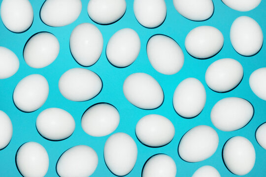 White eggs form a colourful pattern on a bright blue background