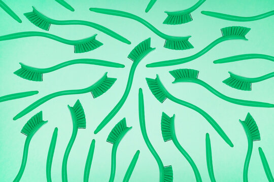 Green cleaning brushes form a pattern on a green background