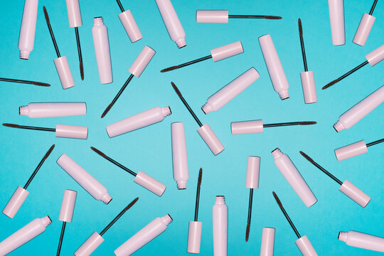 Pink mascara tubes create a playful pattern on a blue background