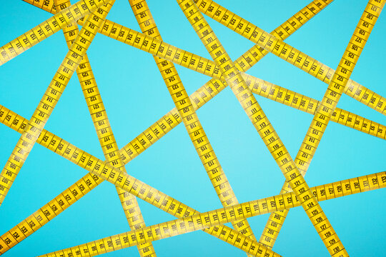 Yellow measuring tapes form an intricate pattern on a blue background
