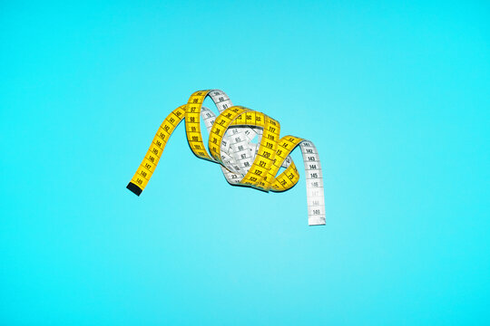 A yellow tape measure lies on a blue background